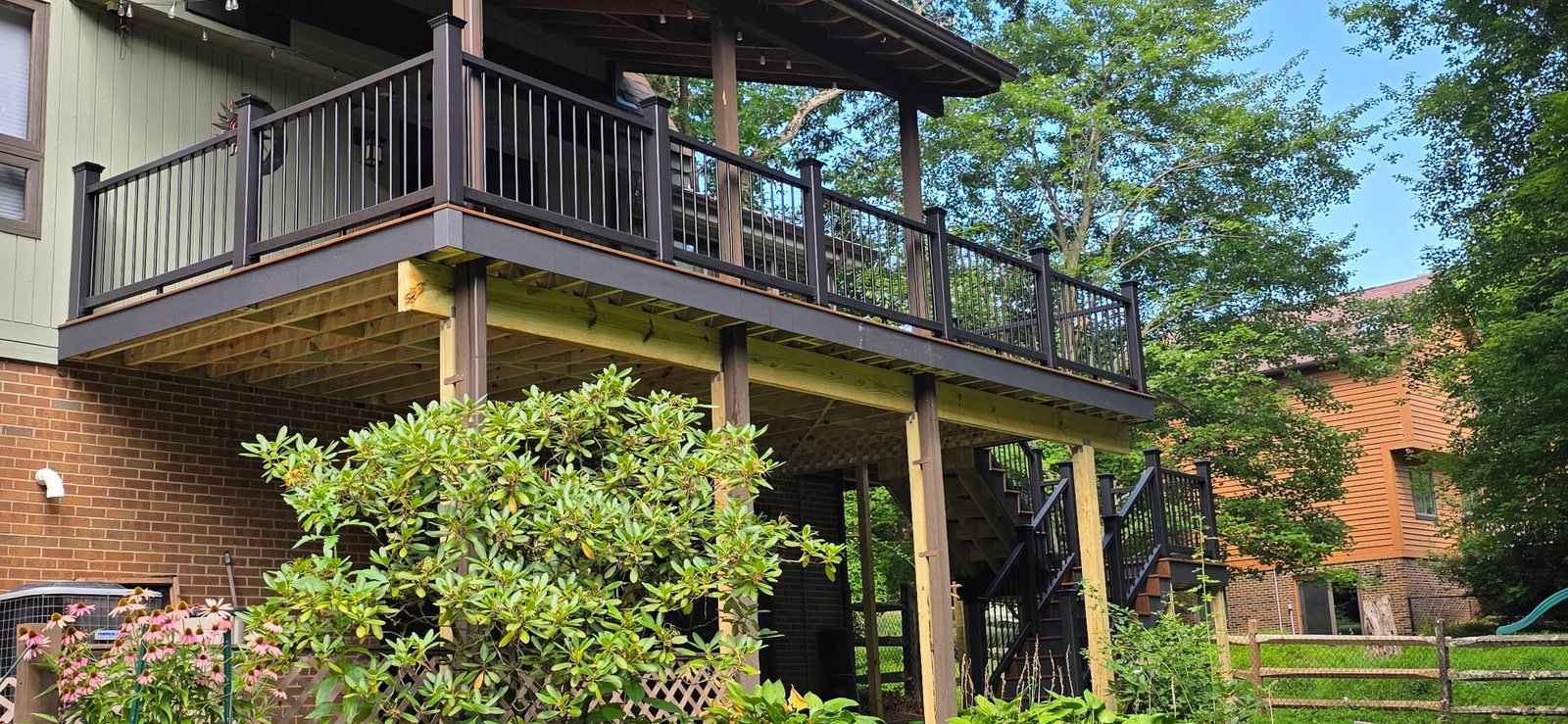 A completed elevated deck with dark railings and stairs